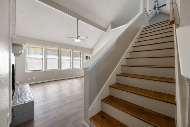 stairway with lofted ceiling, hardwood / wood-style floors, and ceiling fan