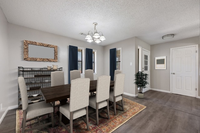 dining space featuring a textured ceiling, an inviting chandelier, and dark hardwood / wood-style flooring