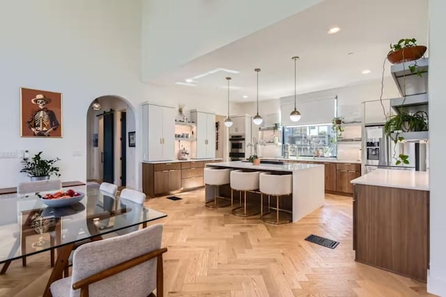 107 Blue Ridge Trl, Austin, TX 78746 - kitchen with arched walkways, stainless steel appliances, a kitchen bar, a kitchen island, and light countertops