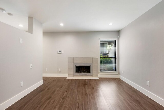 unfurnished living room featuring a tile fireplace and dark hardwood / wood-style flooring