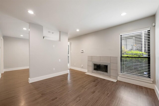 unfurnished living room featuring dark wood-type flooring and a fireplace