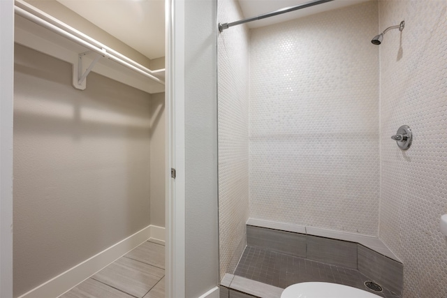 bathroom featuring tiled shower, toilet, and tile patterned flooring