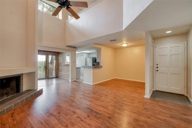 unfurnished living room with a high ceiling, light hardwood / wood-style floors, and ceiling fan