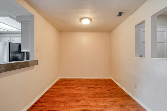 unfurnished room with wood-type flooring and a textured ceiling