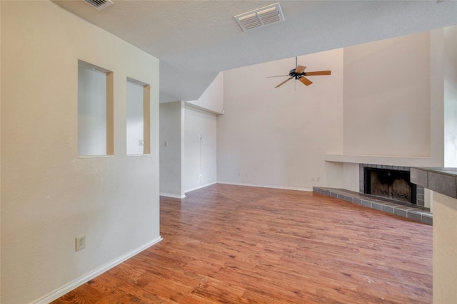 unfurnished living room featuring a fireplace, a textured ceiling, hardwood / wood-style flooring, and ceiling fan