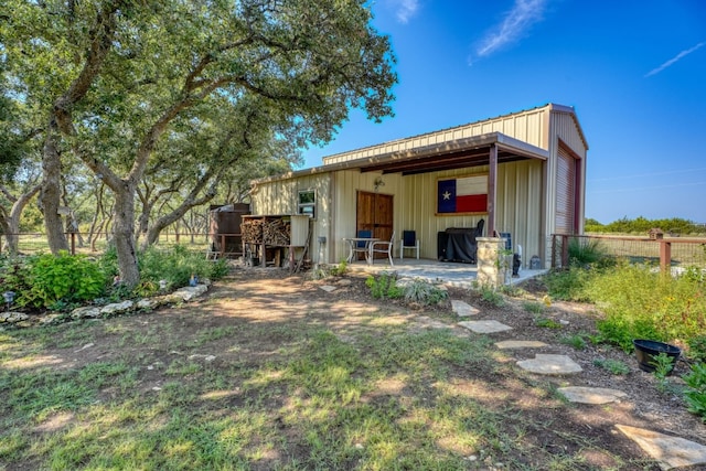 rear view of property featuring a garage, a patio area, and fence