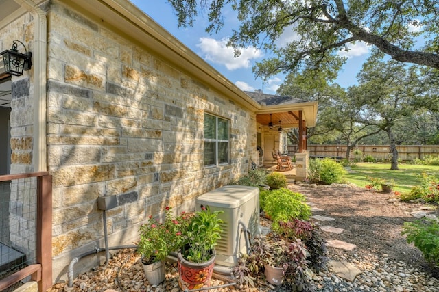 view of home's exterior with stone siding and fence