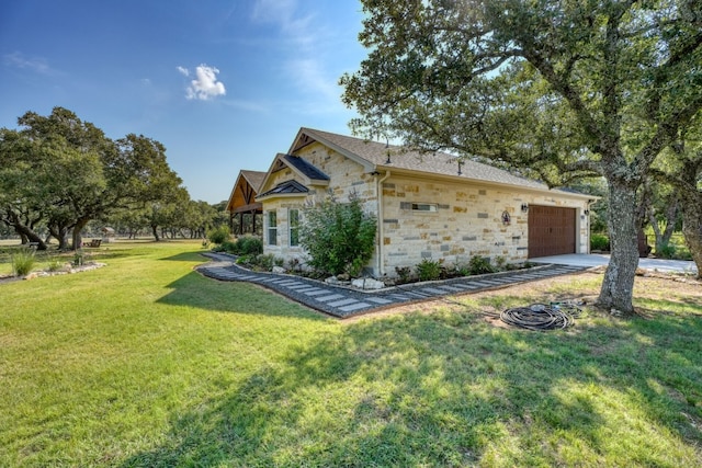 view of side of home featuring stone siding, a yard, an attached garage, and driveway