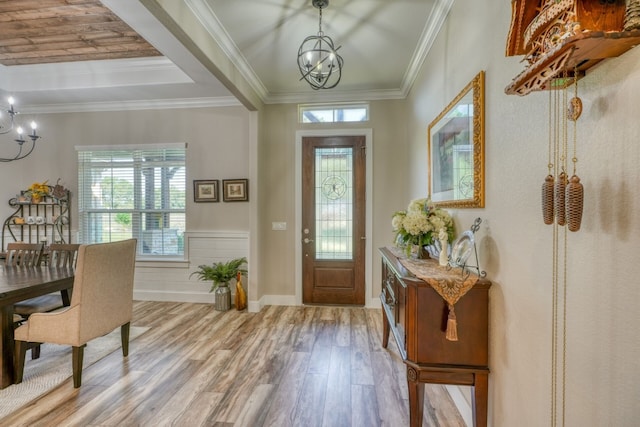 foyer featuring a wealth of natural light, ornamental molding, a notable chandelier, and wood finished floors