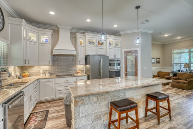 kitchen featuring stainless steel appliances, premium range hood, a sink, white cabinetry, and glass insert cabinets