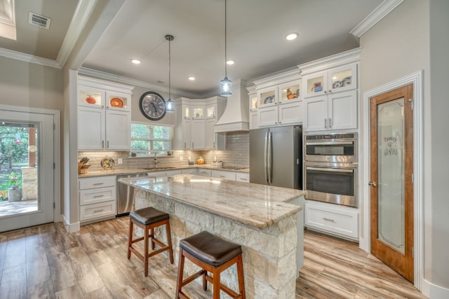 kitchen featuring visible vents, white cabinets, a kitchen island, appliances with stainless steel finishes, and glass insert cabinets