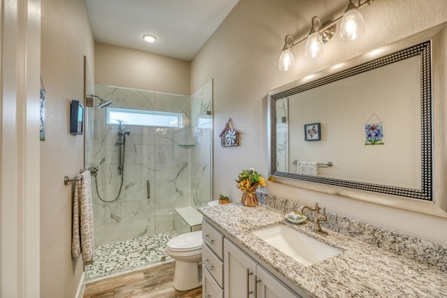 full bathroom featuring toilet, wood finished floors, a marble finish shower, and vanity