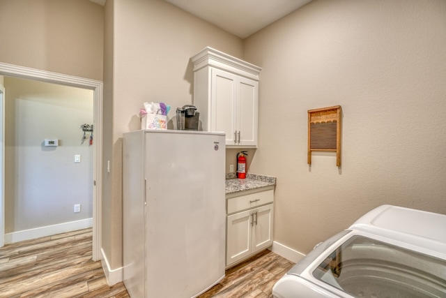 laundry room with baseboards, cabinet space, washer and clothes dryer, and light wood finished floors