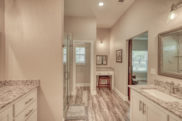 bathroom with wood finished floors, visible vents, vanity, baseboards, and a shower stall