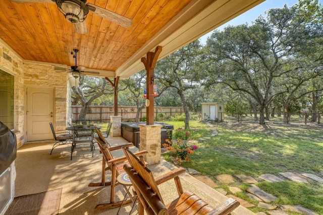 view of patio / terrace with outdoor dining space, ceiling fan, a shed, a fenced backyard, and an outdoor structure