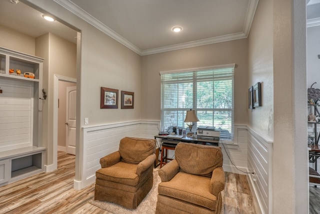 sitting room with light wood-type flooring, ornamental molding, and wainscoting