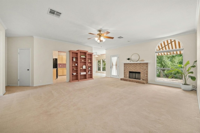 unfurnished living room with light carpet, a brick fireplace, a wealth of natural light, and ceiling fan