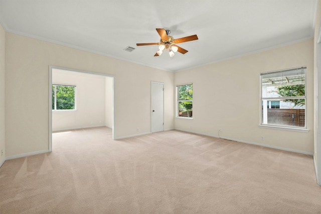 carpeted spare room with a wealth of natural light, ornamental molding, and ceiling fan