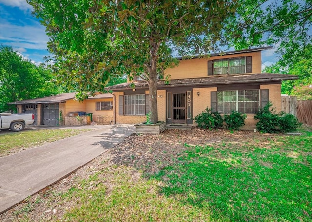 view of front of home with an attached garage, fence, and brick siding