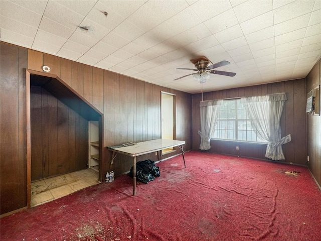 interior space featuring ceiling fan and wood walls