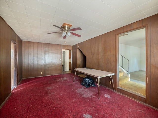 unfurnished bedroom featuring wooden walls, ceiling fan, and carpet floors