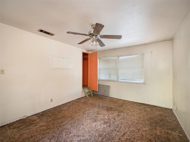 empty room with carpet, visible vents, and a ceiling fan