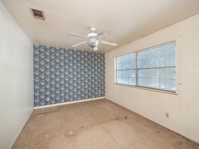 empty room featuring baseboards, visible vents, ceiling fan, and tile patterned floors