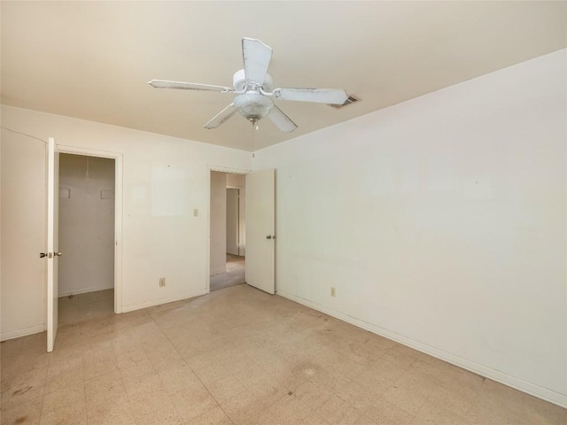 unfurnished bedroom with a walk in closet, light floors, a closet, a ceiling fan, and baseboards