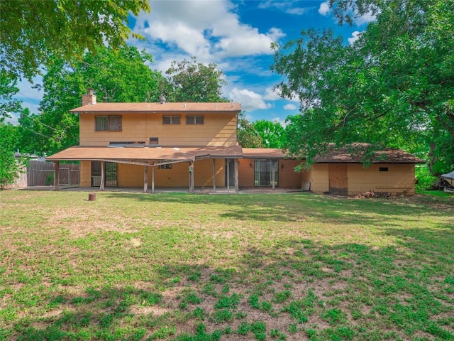 back of house featuring a lawn, a chimney, and fence