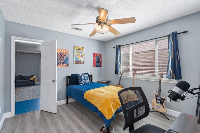 bedroom featuring ceiling fan, light wood-type flooring, and a textured ceiling