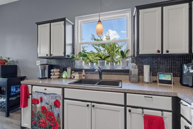 kitchen with hardwood / wood-style floors, backsplash, sink, white dishwasher, and white cabinetry