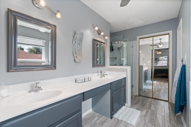 bathroom featuring dual vanity, wood-type flooring, a shower with shower door, a textured ceiling, and ceiling fan