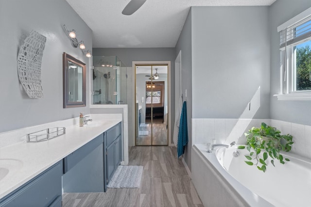 bathroom with a textured ceiling, ceiling fan, hardwood / wood-style floors, and separate shower and tub