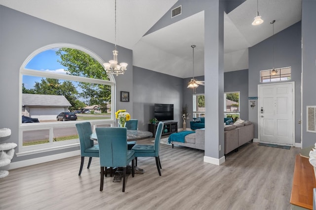 dining space featuring high vaulted ceiling, ceiling fan with notable chandelier, and hardwood / wood-style flooring