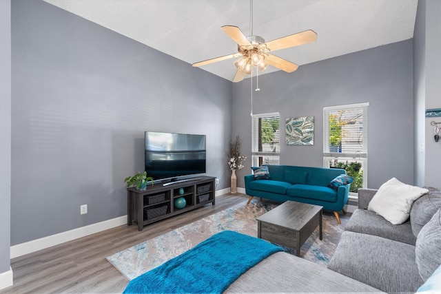 living room with ceiling fan, light wood-type flooring, and high vaulted ceiling