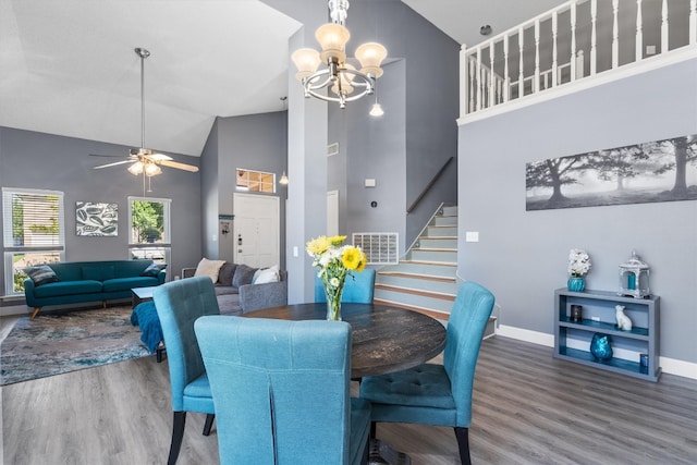 dining room featuring ceiling fan with notable chandelier, hardwood / wood-style flooring, and high vaulted ceiling