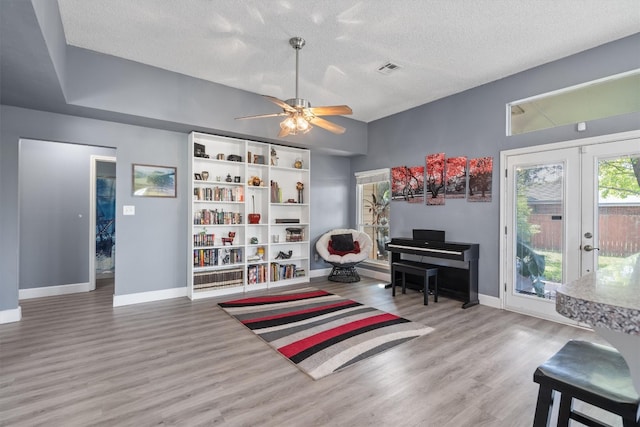 interior space featuring ceiling fan, wood-type flooring, french doors, and a textured ceiling