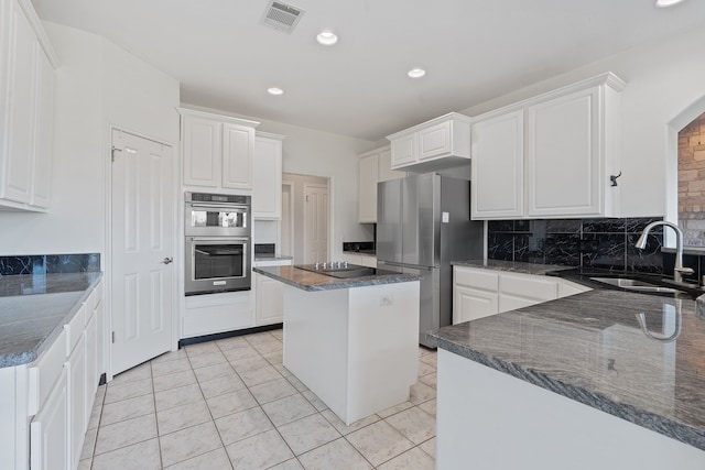 kitchen featuring appliances with stainless steel finishes, sink, a kitchen island, white cabinets, and dark stone counters