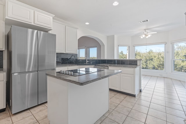 kitchen with stainless steel fridge, white cabinetry, tasteful backsplash, light tile patterned floors, and a center island