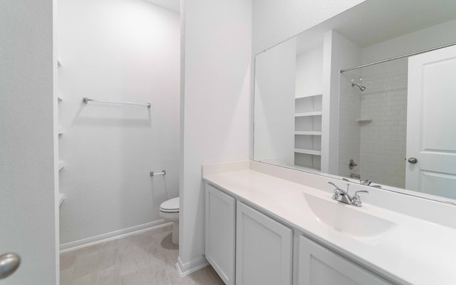 bathroom featuring vanity, tiled shower, and toilet