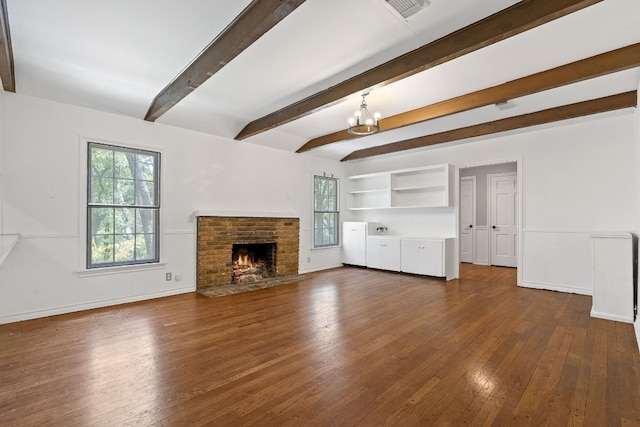 unfurnished living room with a brick fireplace, beamed ceiling, a notable chandelier, and dark wood-type flooring