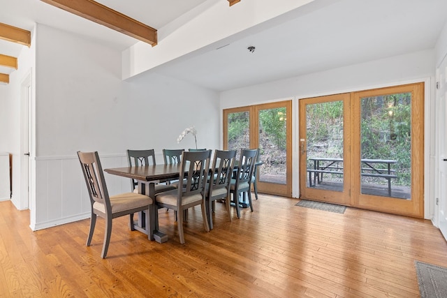 dining room with beam ceiling, light hardwood / wood-style flooring, and french doors