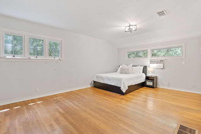 bedroom with an AC wall unit and light hardwood / wood-style floors