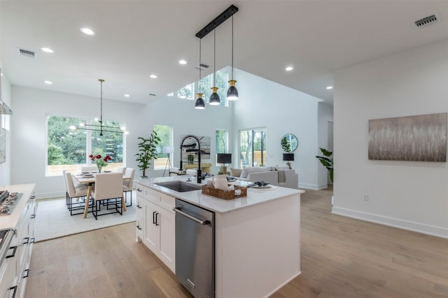 kitchen featuring white cabinets, stainless steel dishwasher, a kitchen island with sink, and light hardwood / wood-style flooring