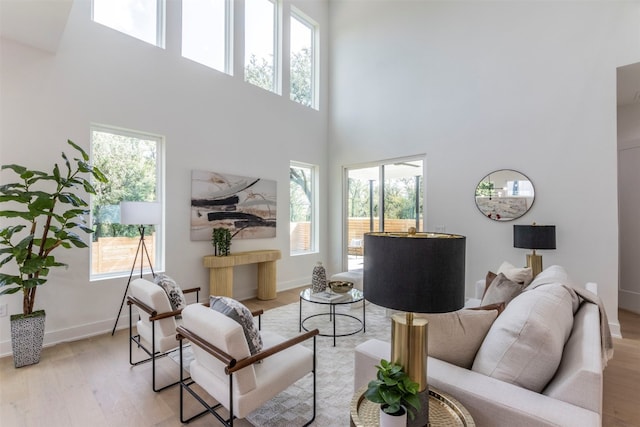 living room featuring a high ceiling, plenty of natural light, and light hardwood / wood-style flooring