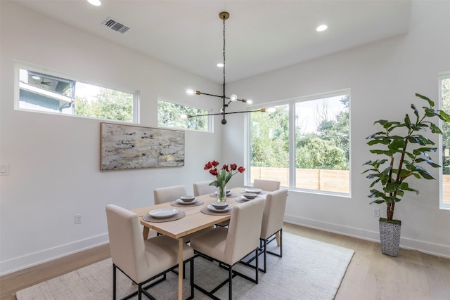 dining room with a wealth of natural light, a notable chandelier, and light wood-type flooring