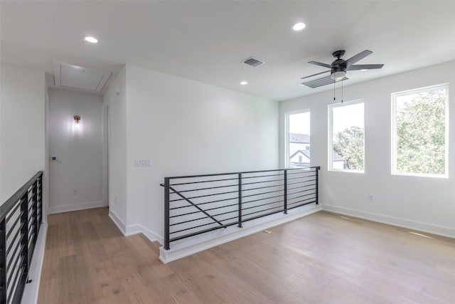 empty room with ceiling fan, light hardwood / wood-style flooring, and a healthy amount of sunlight