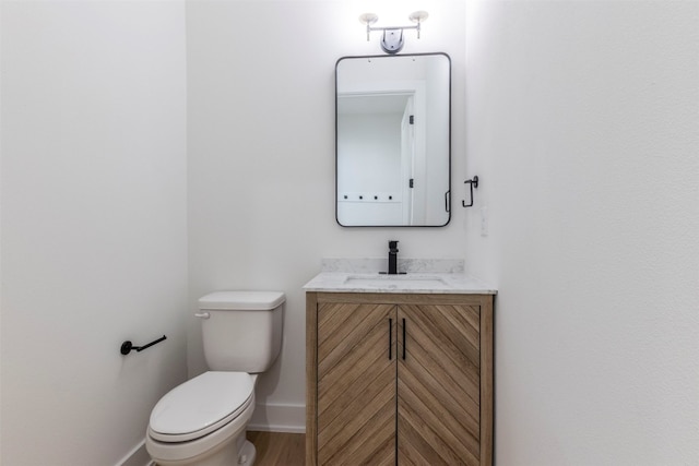 bathroom with toilet, hardwood / wood-style floors, and vanity