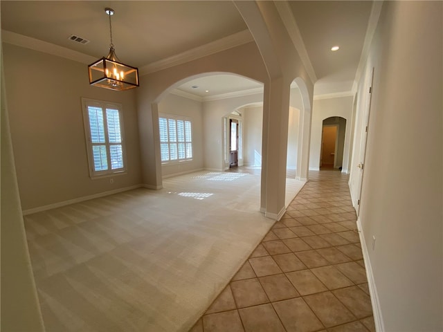 spare room featuring crown molding, a notable chandelier, and light carpet