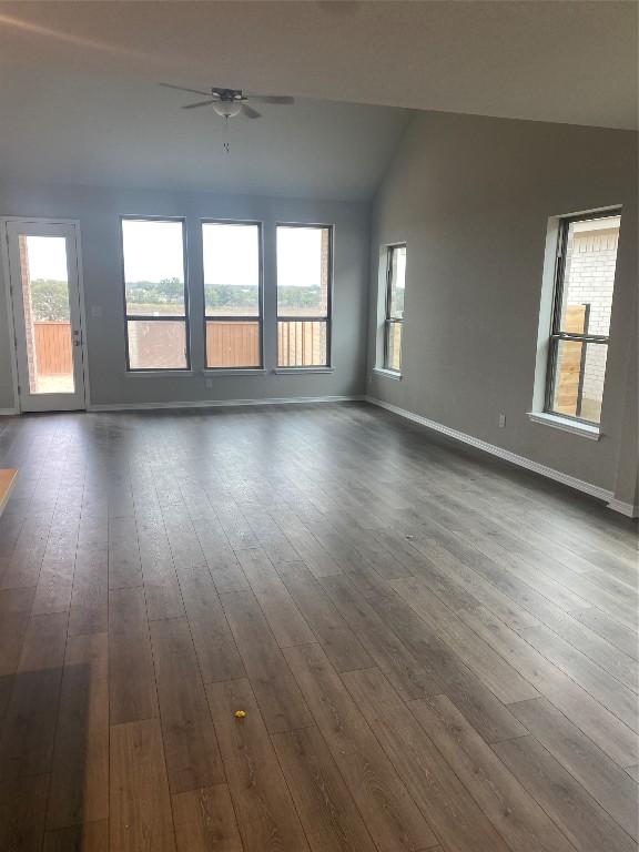 spare room with vaulted ceiling, dark wood finished floors, a ceiling fan, and baseboards